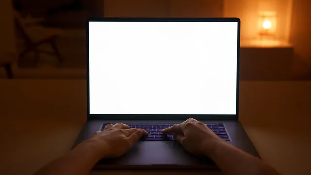 Hands typing on a laptop with a blank screen, creating a cozy and quiet workspace atmosphere indoors. Evaluating account permissions for a multi-brand team