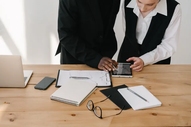 Two professionals collaborating over charts and tablet in a modern office setting. Marketing technology procurement
