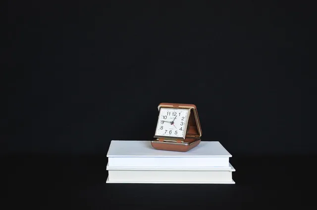 clock, books, stack, time, black background. Planning stack upgrades after a business acquisition
