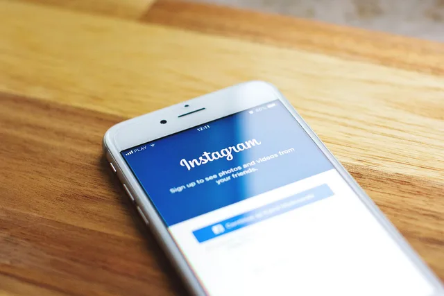 Close-up of a smartphone showing Instagram login on a wooden table. Reviewing administrative access across marketing tools